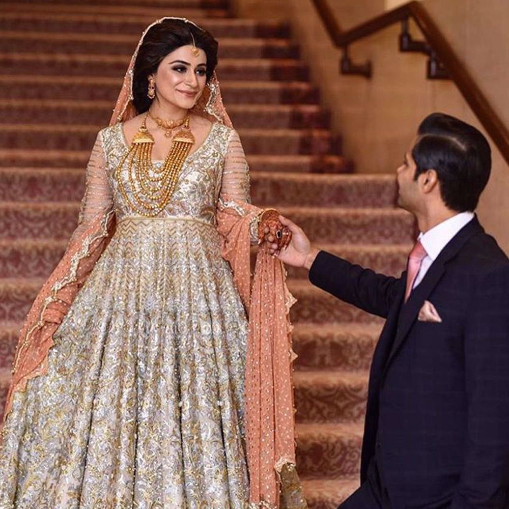 Picture of Manal Shafqat wears an ivory Anarkali paired with a paneled skirts and a peach tulle net dupatta